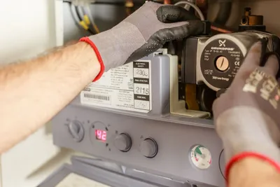 Gas engineer adjusting boiler controls during a safety inspection