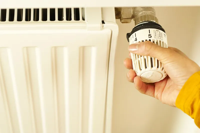 Hand adjusting a radiator thermostatic valve