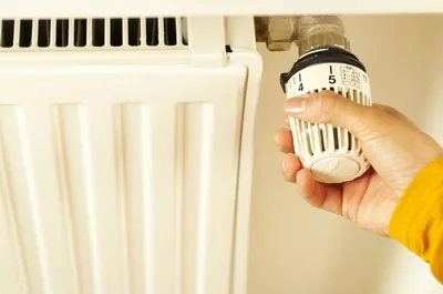 Hand adjusting a radiator thermostatic valve